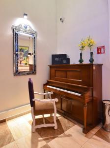 a piano in a room with a chair and a mirror at Hotel Andante in Puebla