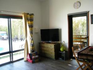 a living room with a flat screen tv on a dresser at Géranium et Manguier Guest House in Saint-Gilles-les Hauts