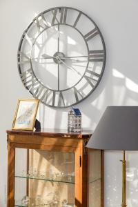 une grande horloge sur un mur au-dessus d'une table avec une lampe dans l'établissement Chambre d'Hôtes Les Clés des Places, à Arras