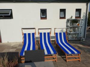 3 chaises bleues et blanches assises sur un patio dans l'établissement Appartement Soigner!, à Egmond-Binnen