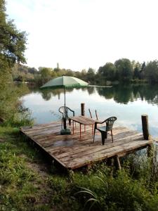 a picnic table with an umbrella on a dock on a lake at Room Galina in Duga Resa