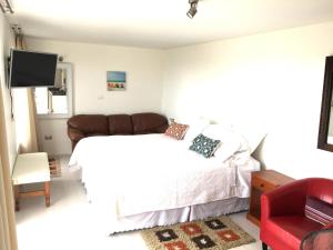 a bedroom with a white bed and a red chair at Alojamiento Independiente in Zapallar