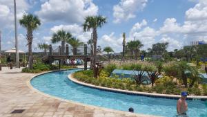 Ein Mann steht in einem Pool in einem Resort. in der Unterkunft 4 Bedroom Private Lakefront Town Home at Storey Lake near Disney World Parks in Kissimmee