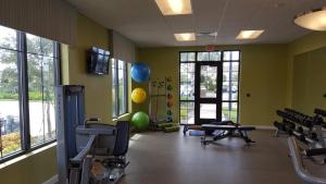 ein Fitnessstudio mit Trainingsgeräten in einem Raum mit Fenstern in der Unterkunft 4 Bedroom Private Lakefront Town Home at Storey Lake near Disney World Parks in Kissimmee