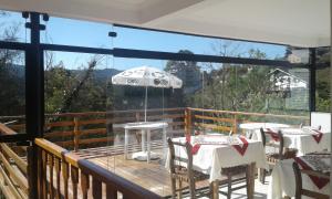 a balcony with tables and chairs and an umbrella at Pousada La Sierra in Campos do Jordão