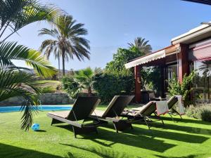 a yard with lounge chairs and a pool at Anfi Tauro Rentals in La Playa de Tauro