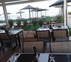 a restaurant with tables and chairs with a view of the beach at Hotel Roca Bella in Es Pujols