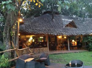 Aitong的住宿－Wilderness Seekers Ltd Trading As Mara River Camp，设有带桌椅的茅草建筑的度假酒店