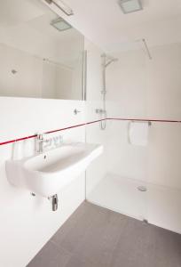 biała łazienka z umywalką i wanną w obiekcie Montis Hotel & Spa w mieście Poniatowa