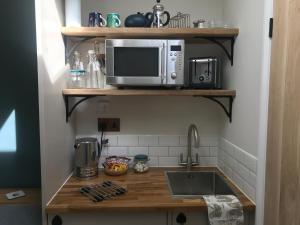a kitchen with a microwave and a sink at Corner House Luxury BnB in Little Dunmow