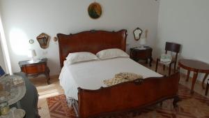 1 dormitorio con 1 cama grande de madera y 2 mesas en B&B Il Glicine, en Badia Polesine