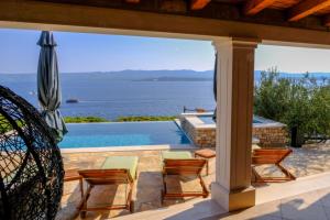a patio with chairs and an umbrella and a swimming pool at Villa Lucija Bol in Bol
