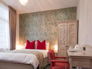 1 dormitorio con cama con almohadas rojas y escritorio en W12 Rooms, en Londres