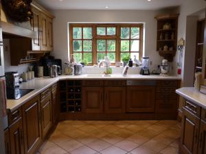 a kitchen with wooden cabinets and a sink and a window at One Pelham Grove Bed & Breakfast in Stocking Pelham