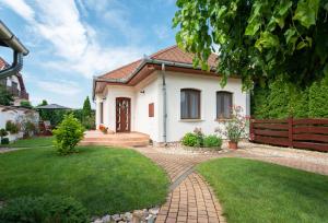 a white house with a fence and a lawn at Hajdu Apartman 2. in Hajdúszoboszló