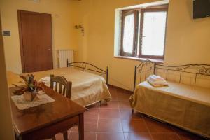 Zimmer mit 2 Betten, einem Tisch und einem Fenster in der Unterkunft Il Vecchio Frantoio in Stella Cilento