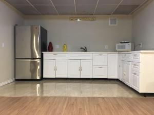 a kitchen with white cabinets and a stainless steel refrigerator at Seaview White House in Stratford