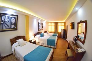 a hotel room with two beds and a mirror at El Gran Hotel de Pereira in Pereira