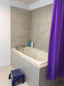 a bath tub in a bathroom with a purple shower curtain at Seaview White House in Stratford