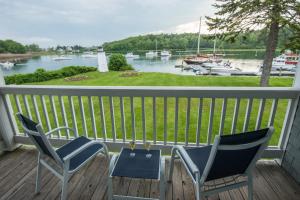 two chairs and a table on a deck with a view of a harbor at The Nonantum Resort in Kennebunkport