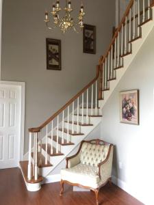 a staircase with a chair and a chandelier at Seaview White House in Stratford