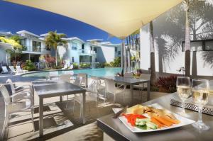 una mesa con un plato de comida y copas de vino en Sand Dunes Resort Accommodation, en Marcoola