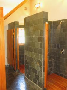 y baño con pared de piedra y ducha. en La Confluencia Lodge en El Bolsón