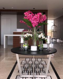uma mesa com um vaso de flores cor-de-rosa em قولدن سكوير طريق الرياض Golden Square Riyadh Road em Khamis Mushayt