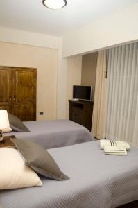 two beds in a room with a tv and a bed sidx sidx sidx at Nativa suites in Cochabamba