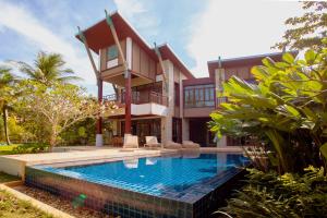 a house with a swimming pool in front of a house at Amatapura Beachfront Villa 1, SHA Certified in Ao Nam Mao