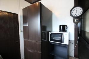 a kitchen with a microwave and a clock on the wall at Yadokari House in Okayama