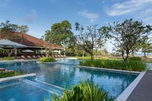 a pool at a resort with chairs and trees at Solina Beach & Nature Resort in Carles