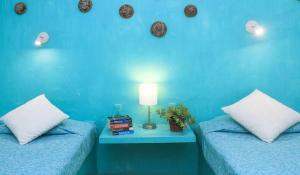 a blue room with two beds and a table with a lamp at Casa de Don Pablo Hostel in Oaxaca City