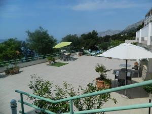 eine Terrasse mit einem Sonnenschirm, Tischen und Stühlen in der Unterkunft Garni IVANAC in Brela