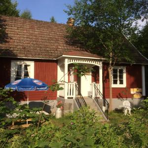 a small red and white house with a blue umbrella at Mormors Bakeri – B&B in Asarum