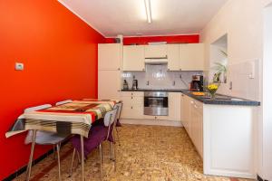 une cuisine aux murs orange et une table avec des chaises dans l'établissement Chez Lisa avec jaccuzi, à Vielsalm