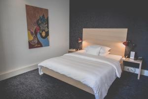 Un dormitorio con una gran cama blanca y una pintura en Hotel Mon Repos en Ginebra
