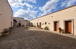 une cour avec des bâtiments blancs et un ciel bleu dans l'établissement Masseria Li Campi, à Cavallino di Lecce