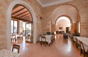una sala da pranzo con tavoli e sedie in un edificio di Masseria Li Campi a Cavallino di Lecce
