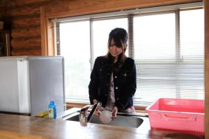 a woman standing in the kitchen washing dishes at Okinoshima Resort Island Park Hotel in Tsudo