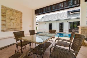 une salle à manger avec une table et des chaises et une piscine dans l'établissement 4 Bedroom Private Bali Style Villa HH6, à Hua Hin