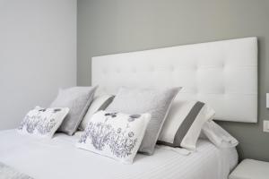 Una cama blanca con cuatro almohadas. en Seafront La Malagueta II, en Málaga
