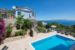 a villa with a swimming pool in front of a house at Villa Bella Vista - apartments in Labin