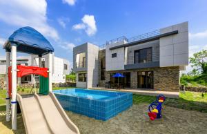 ein Haus mit einem Pool und einem Spielplatz in der Unterkunft Chandelier Pension in Jeju-do