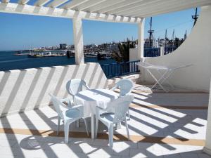 a white table and chairs on a patio with a view of the water at Marina Cap Monastir- Appart'Hôtel in Monastir