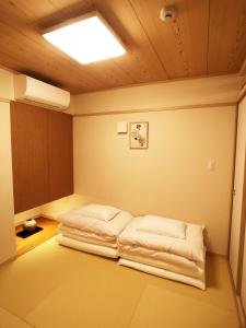 two beds in a room with a ceiling at harper house in Osaka