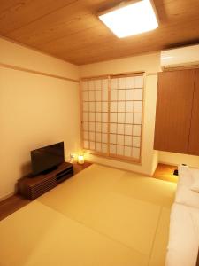 ein Wohnzimmer mit einem TV und einem Sofa in der Unterkunft harper house in Osaka