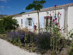 un jardin en face d'une maison blanche ornée de fleurs dans l'établissement Hotel Residence Les Alizes, à Grand-Village-Plage