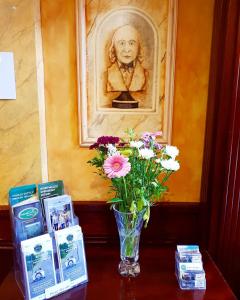 a vase of flowers sitting on a table with a picture at The Gandon Inn in Emo