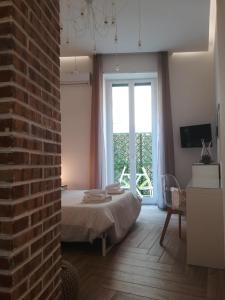 een slaapkamer met een bed en een bakstenen muur bij Il Tesoro di SanGennaro in Napels